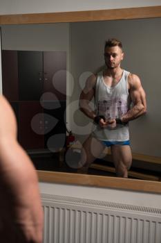 Healthy Man In Undershirt Standing Strong At Gym And Flexing Muscles - Muscular Athletic Bodybuilder Fitness Model Posing After Exercises