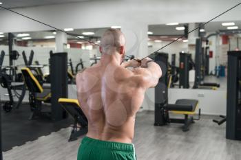 Man Bodybuilder Is Working On His Back With Cable Crossover In A Gym