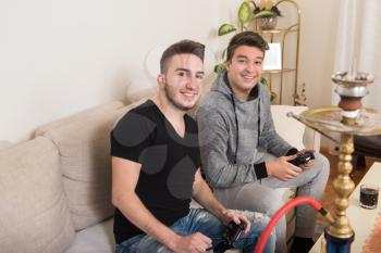 Two Brothers or Friends Playing Video Games Together as They Relax on a Couch in the Living Room