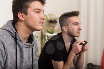 Two Brothers or Friends Playing Video Games Together as They Relax on a Couch in the Living Room