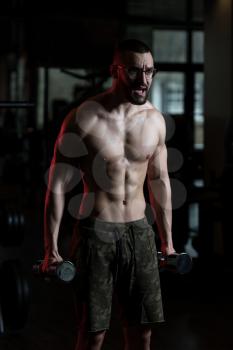 Handsome Man Wearing Glasses Working Out Biceps In A Dark Gym - Dumbbell Concentration Curls