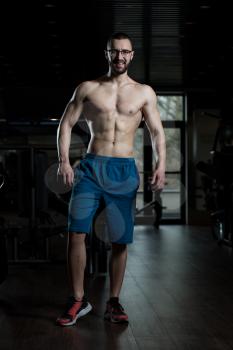 Handsome Geek Man Standing Strong In The Gym And Flexing Muscles - Muscular Athletic Bodybuilder Fitness Model Posing After Exercises