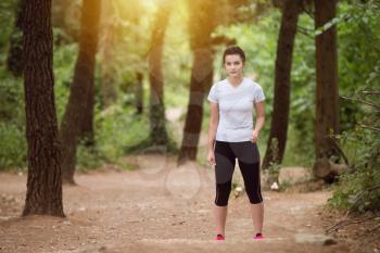 Portrait of a Young Woman Running In Wooded Forest Area - Training And Exercising For Trail Run Marathon Endurance - Fitness Healthy Lifestyle Concept