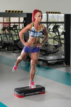 Young Woman Athlete Doing Exercise On Stepper As Part Of Bodybuilding Training