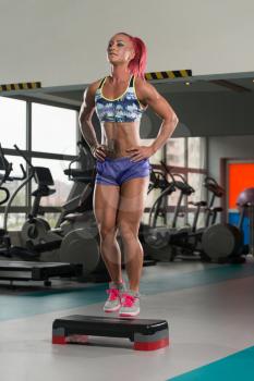 Young Woman Athlete Doing Exercise On Stepper As Part Of Bodybuilding Training