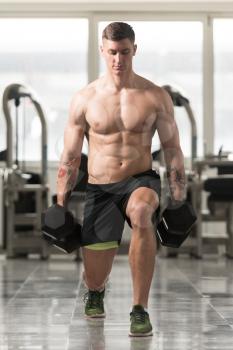 Young Man Working Out Legs With Dumbbells In A Gym - Squat Exercise