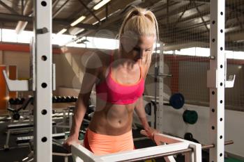Young Muscular Fitness Woman Doing Heavy Weight Exercise For Triceps And Chest on Parallel Bars In The Gym