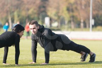 Young Couple Doing Pushups in City Park Area - Training and Exercising for Endurance - Fitness Healthy Lifestyle Concept Outdoor