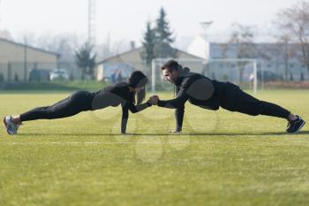 Attractive Couple Doing Push Up in City Park Area - Training and Exercising for Endurance - Fitness Healthy Lifestyle Concept Outdoor