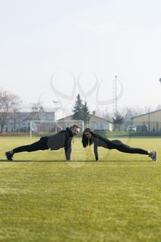 Young Couple Doing Pushups in City Park Area - Training and Exercising for Endurance - Fitness Healthy Lifestyle Concept Outdoor