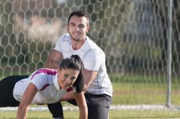 Attractive Couple Doing Crossfit With Trx Fitness Straps in City Park Area - Training and Exercising for Endurance - Healthy Lifestyle Concept Outdoor
