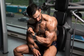 Healthy Young Tattoo Man Sitting Strong In The Gym And Flexing Muscles - Muscular Athletic Bodybuilder Fitness Model Posing After Exercises