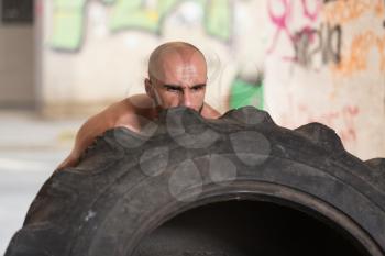 Young Muscular Man With Truck Tire Doing Crossfit Style Workout Turning Tire Over