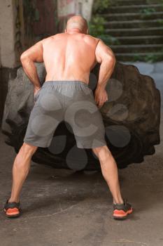 Young Muscular Man With Truck Tire Doing Crossfit Style Workout Turning Tire Over