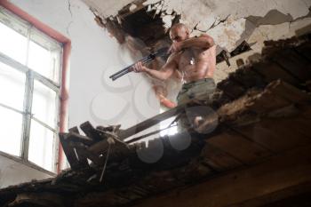 Action Hero Muscled Man Holding Machine Gun - Standing In Abandoned Building Wearing Army Pants