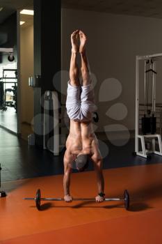 Bodybuilder Doing Handstand Push Ups On Barbell As Part Of Bodybuilding Training In Gym