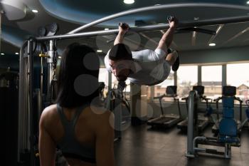 Personal Trainer Showing Young Woman How To Train Pull Ups - Chin-Ups In The Gym