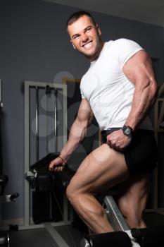 Strong Man In The Gym And Exercising Quadriceps And Glutes On Machine - Muscular Athletic Bodybuilder Fitness Model Exercise