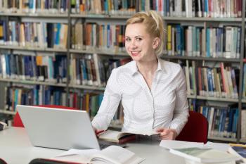 Portrait of an Attractive Student Doing Some School Work With a Laptop in the Library