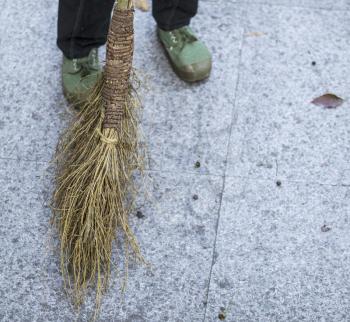 Person sweeping with traditional Chinese broom with mess on floor