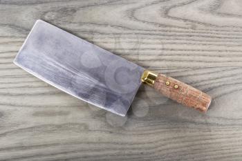 Old butcher knife on aging ash wood background