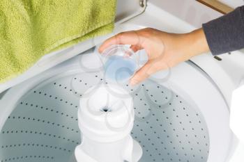 Horizontal photo female hand putting liquid soap into washing machine for laundry 