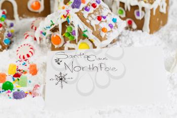 Closeup horizontal photo of letter to Santa with Gingerbread houses, surrounded by powdered snow in background 