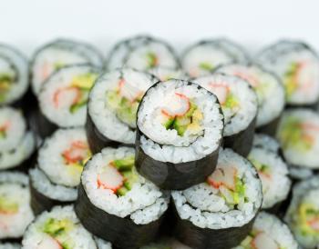 Closeup photo of Single California hand roll sushi on top of pile of additional sushi 