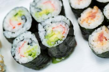 Closeup horizontal top view photo of freshly handmade sushi rolls in white plate 