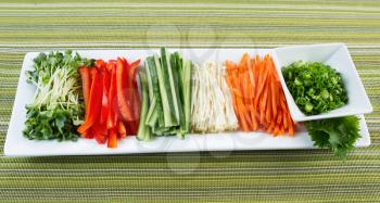 Horizontal photo of fresh sushi ingredients place in long plate with textured table cloth underneath