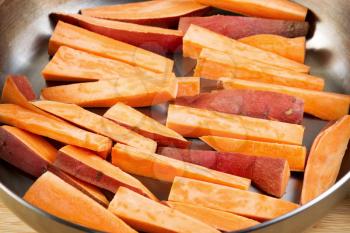 Horizontal photo of freshly cut Yams in stainless steel frying pan ready for cooking into French fries
