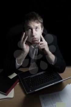 Vertical image of business man, ready to lose his temper while on his cell phone, working late with black background 