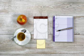 Top view of business office objects with food and drink on rustic white wooden desktop 