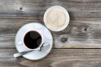 Overhead view of freshly brewed black coffee with spoon and cup of organic sugar on vintage wood 