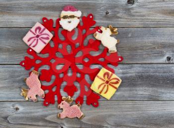 Top view of Christmas cookies surrounding large red snowflake with rustic wood underneath
