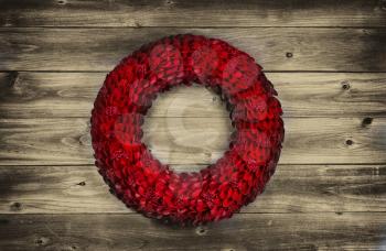 Vintage concept of a wooden petal red holiday wreath on rustic wood 
