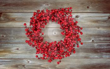 Vintage concept of a red berry holiday wreath on rustic wood