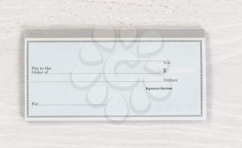 Close up of blank checkbook on white wooden desktop. Layout in horizontal format.