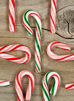 Christmas candy canes on rustic wood. Layout in vertical format with canes in and out of frame.