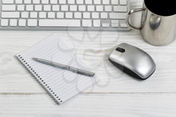 White desktop with partial keyboard, mouse, coffee cup, paper and pen. Horizontal layout with silver color theme.  