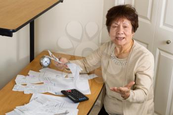 Senior woman expressing extreme anger while working on her financial bills. In debt concept. 
