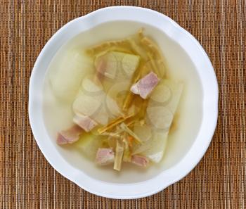 High angled view of Asian soup consisting of pork, bamboo shoots and cabbage vegetable on bamboo mat. 