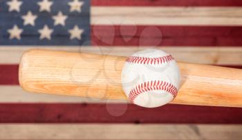 Close up of baseball hitting wooden bat with painted boards of USA flag.  