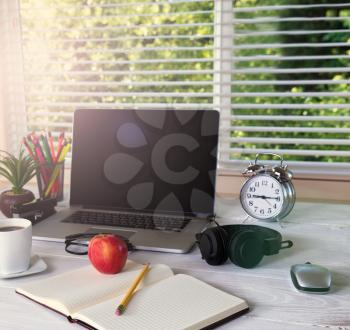 Working desktop in front of large window with bright daylight and trees in background. Light effect applied to image. 