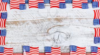 Small USA flags forming complete border on red, white and blue rustic boards. Fourth of July holiday concept for United States of America.  