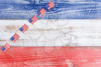 Small USA flags stacked in rising formation on red, white and blue rustic boards. Fourth of July holiday concept for United States of America.  