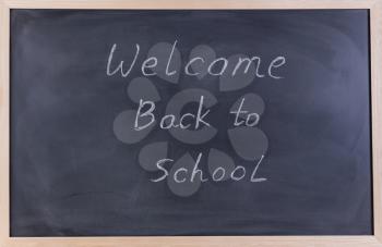 Back to school concept with welcome back to school message on erased black chalkboard. 