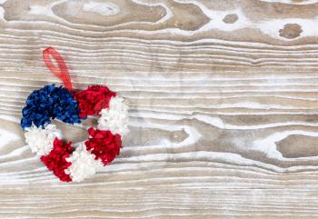 Holiday wreath, heart shaped, in USA national colors on rustic white wooden boards. Fourth of July holiday concept for United States of America.  