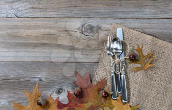 Fall dinner place setting for Thanksgiving holiday in horizontal layout on rustic wooden boards. 