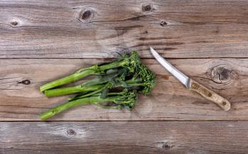 Fresh Chinese broccoli and paring knife on rustic wood in flat lay format